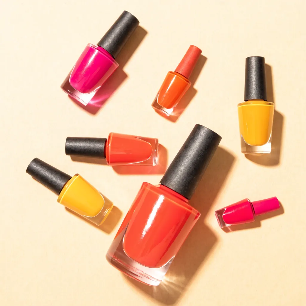 Flat lay of nail polish bottles in coral, pink, tangerine and butter yellow