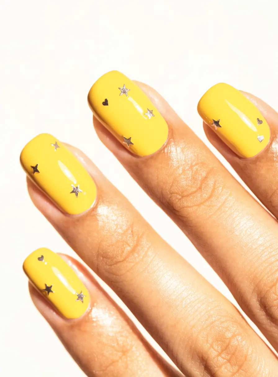 Butter-yellow nails with tiny star and heart decals